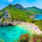 A breathtaking view of Porto Timoni Beach in Corfu, Greece, featuring turquoise waters, lush green hills, and a hidden twin cove perfect for swimming and snorkeling.